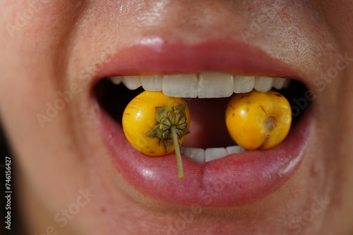 Muruci fruits, also known as murici (Byrsonima crassifolia, Malpighiaceae) in a woman's mouth. The tropical yellow fruits are sweet and have a special flavour. Solimoes, Rio Tapajos, Brazil. photo