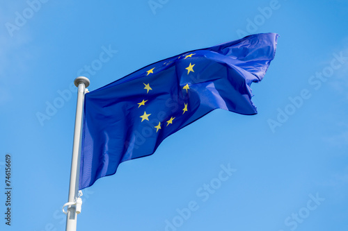 European union flag waving in the wind against bright blue sky.