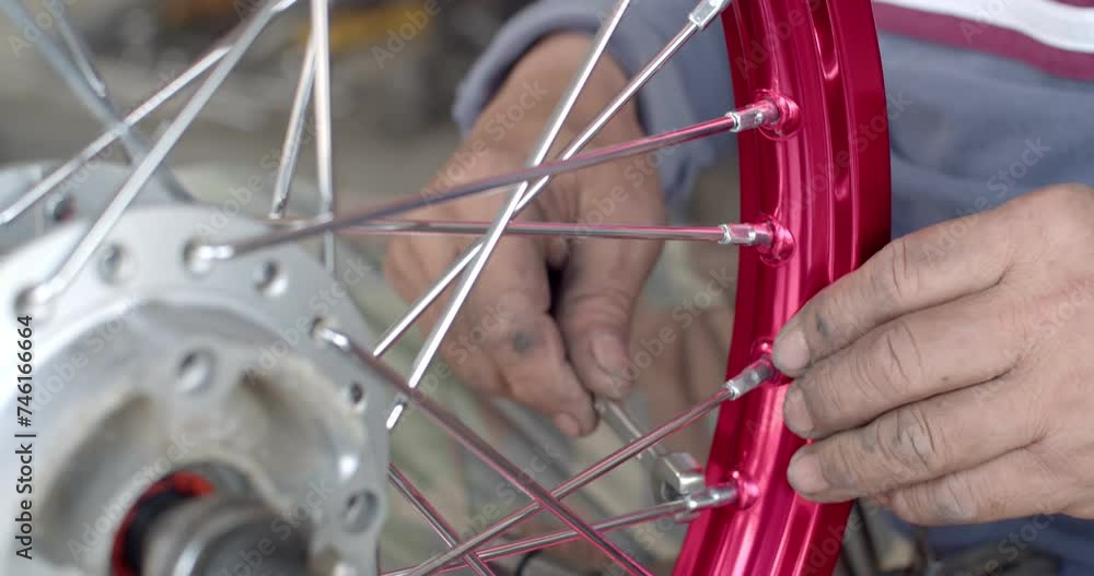 High angle An Asian male working motorcycle wheel has spokes weave up