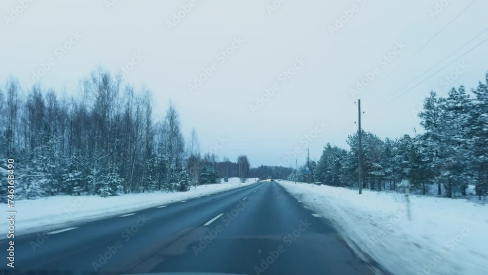 Snow-covered road adventure: POV car driving during winter in the forest during the daytime Snow-covered road adventure: POV car driving during winter in the forest during the daytime
