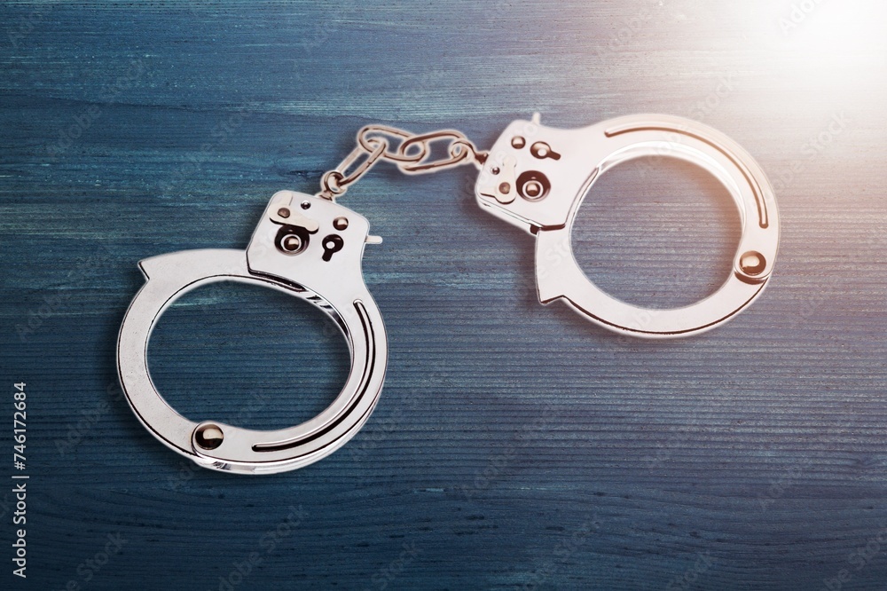 A pair of steel handcuffs on desk surface A pair of steel handcuffs on desk surface