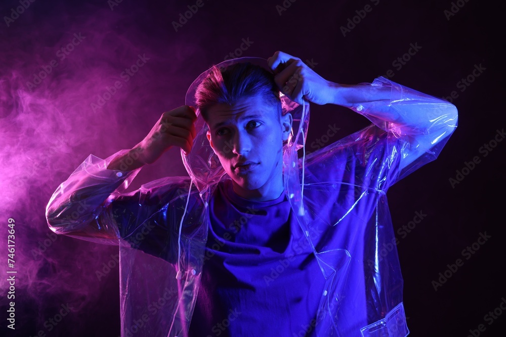 Young man wearing clear coat in neon lights with smoke effect