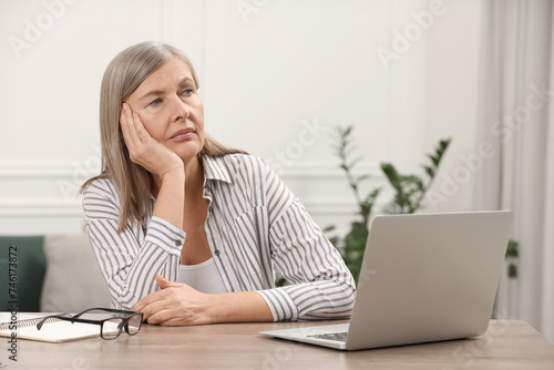 Menopause  mood changes. Sad woman at wooden table indoors