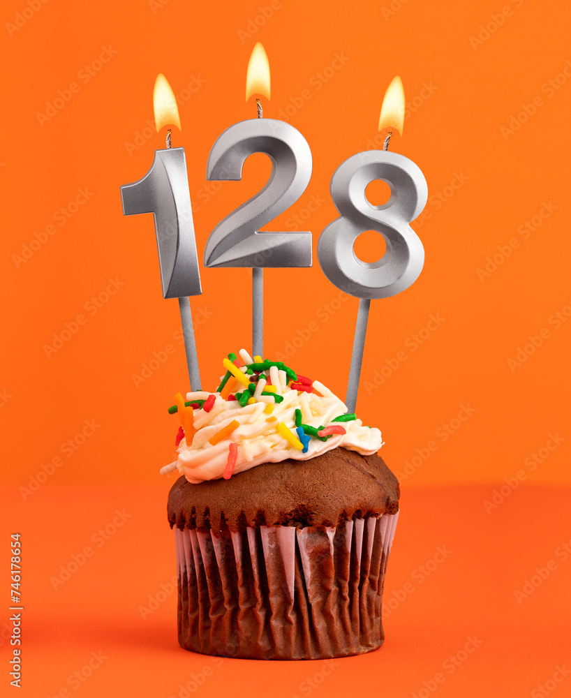 Number 128 candle - Birthday cupcake on orange background
