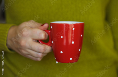 Woman hands holding a cozy red mug