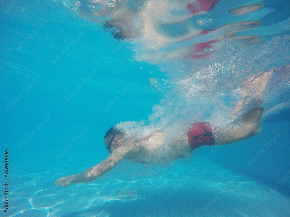 Beard man with glasses diving in a pool