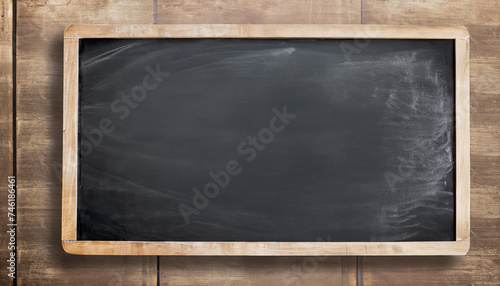 Empty blank black chalkboard with chalk traces; old wooden table surface background