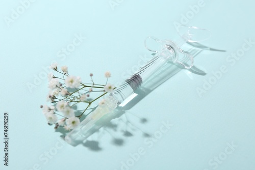 Cosmetology. Medical syringe and gypsophila on light blue background