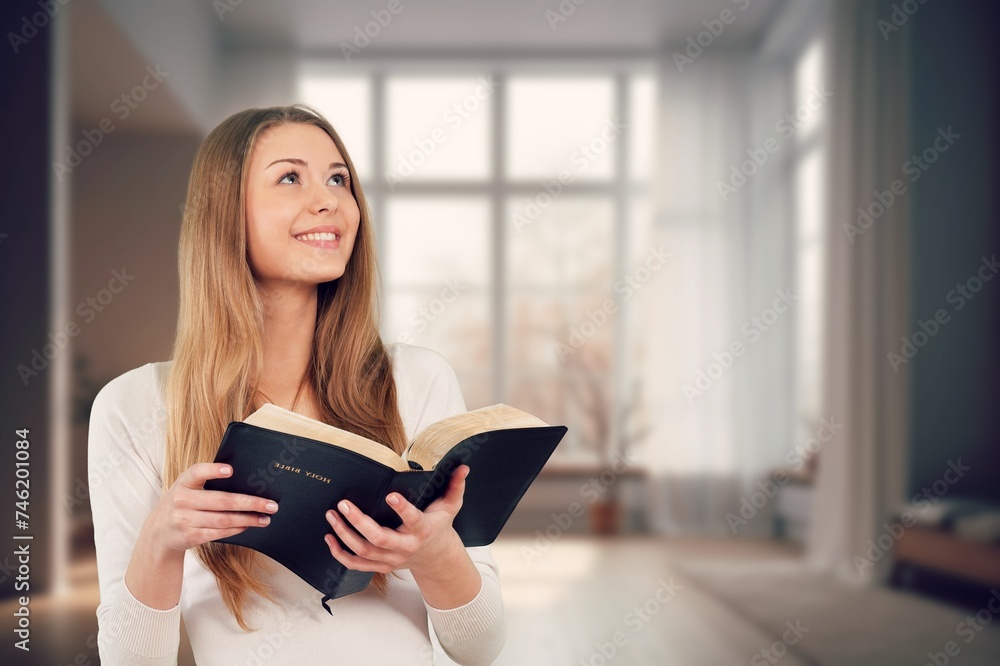 A woman holding a Bible book and praying. A woman holding a Bible book and praying.