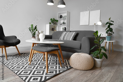 Interior of stylish living room with grey sofa, coffee table and glowing lamps