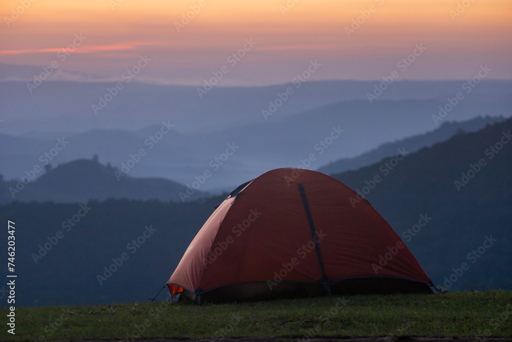 Adventurer tents during overnight camping site at the beautiful scenic sunset view point over layer of mountain for outdoor adventure vacation travel concept