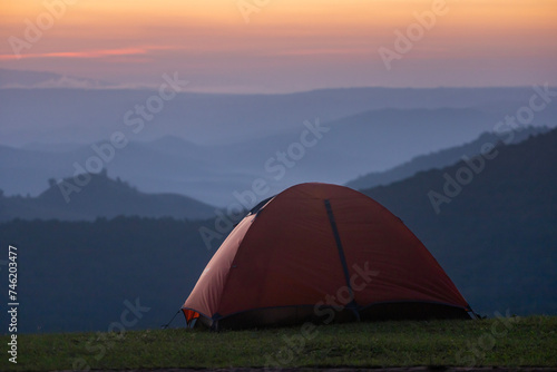 Adventurer tents during overnight camping site at the beautiful scenic sunset view point over layer of mountain for outdoor adventure vacation travel concept