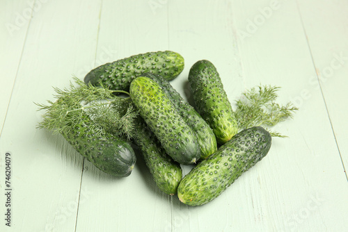 Heap of fresh cucumbers with dill on green wooden background