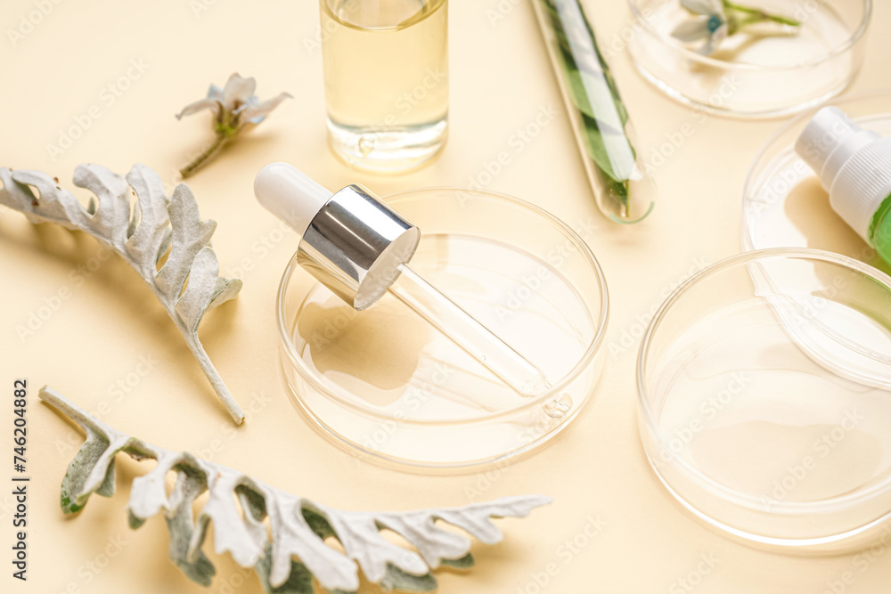 Petri dishes with bottles of cosmetic products and herbs on yellow background