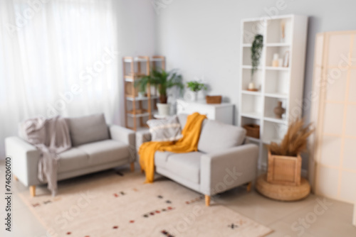 Blurred view of modern living room with grey sofas