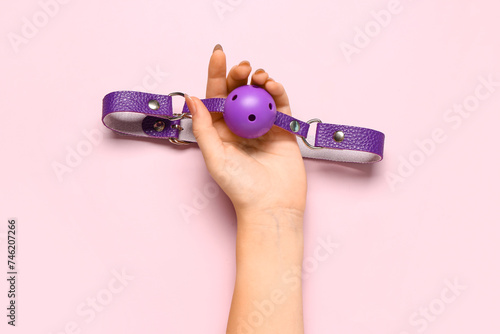 Female hand with whip from sex shop on pink background
