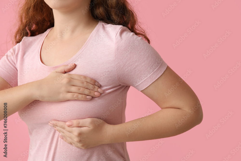 Young woman checking her breast on pink background, closeup. Cancer awareness concept Young woman checking her breast on pink background, closeup. Cancer awareness concept
