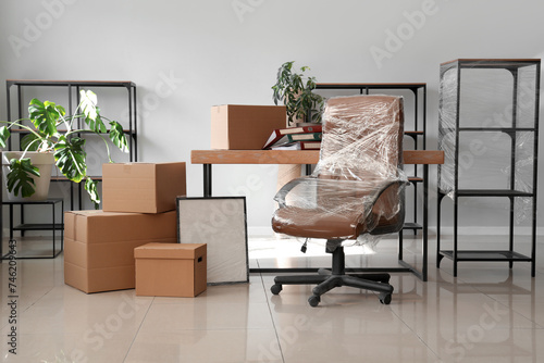 Interior of office with chair wrapped in stretch film and cardboard boxes on moving day photo