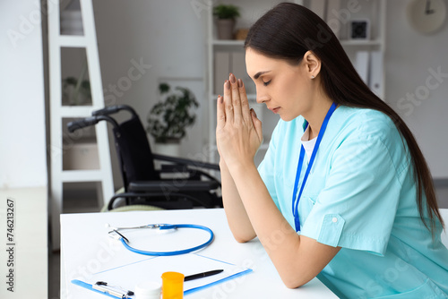 Female nurse praying at tab...