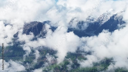 Snowy peaks wonderful natural landscape with blue sky. Drone flying above clouds covering mountain summit. Paradise mountain range in heaven cloudscape. Evergreen forest in Washington nature park photo