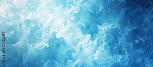 A beautiful abstract background featuring clear blue gradient colors and a glass texture resembling a fantasy, set against a backdrop of fluffy white clouds in the sky. © AkuAku