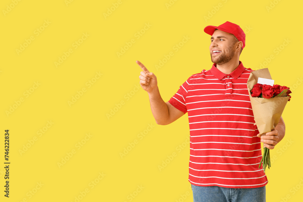 Delivery man with flowers pointing at something on yellow background