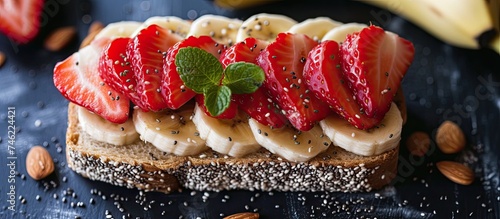 A piece of bread topped with sliced strawberries and bananas, creating a nutritious morning sandwich filled with strawberry, almond, banana, and chia seed. photo