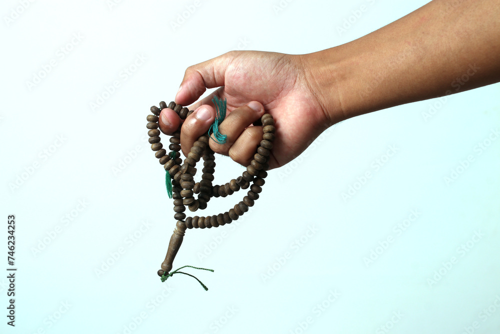 Muslim hand holding wooden prayer beads or Tasbih for dhikr during Ramadan with empty copy space for text, isolated on a white background Muslim hand holding wooden prayer beads or Tasbih for dhikr during Ramadan with empty copy space for text, isolated on a white background