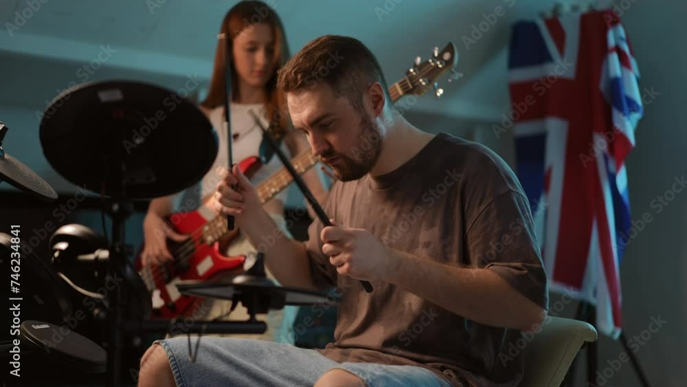 Slow motion. Close-up. A man sits and plays an electronic drum kit, and a young girl plays a bass guitar. Rhythm section during a rehearsal at a music school Slow motion. Close-up. A man sits and plays an electronic drum kit, and a young girl plays a bass guitar. Rhythm section during a rehearsal at a music school
