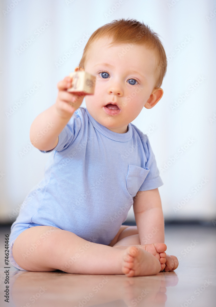 Baby, portrait and playing with wooden blocks or toys for childhood development on a gray studio background. Little boy, cute toddler or child on floor with shape or cube for building or learning