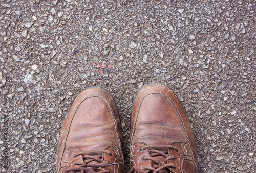 Old brown leather shoes on cement floor.
