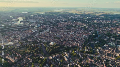 A sprawling cityscape during golden hour, with rivers and greenery, aerial view