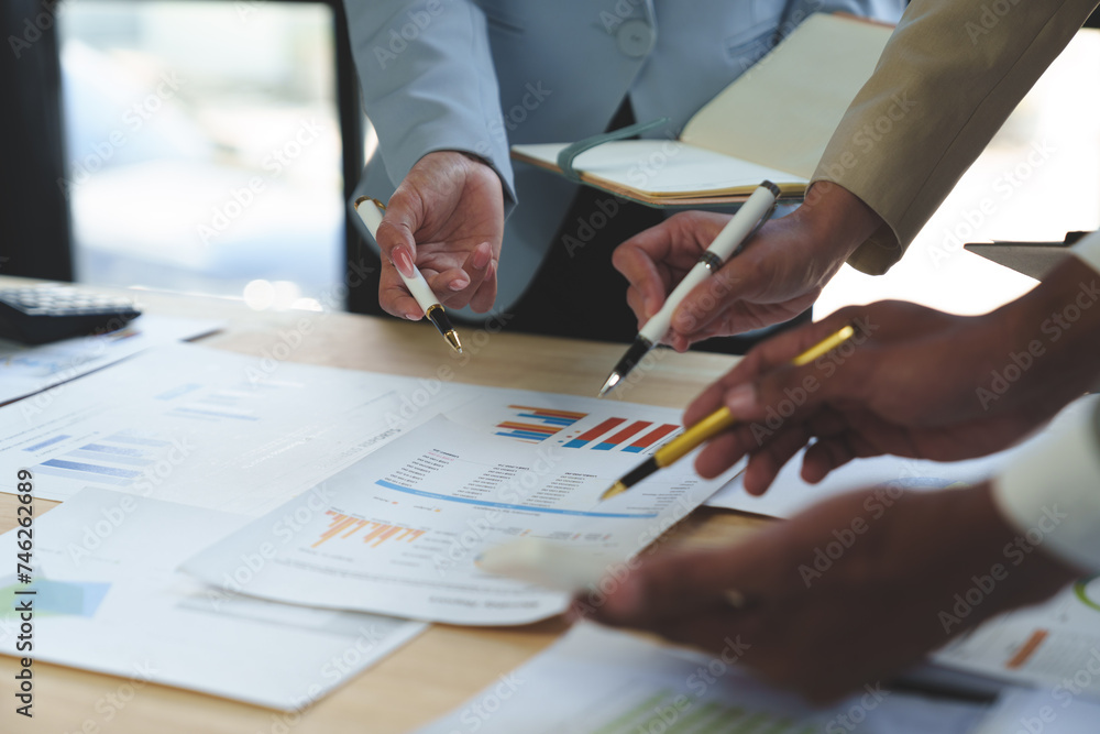 Group of business people meeting, discussion, brainstorming, pointing at graphs and charts to analyze market data, calculating balance sheets, accounts, net profits to plan company sales strategies. Group of business people meeting, discussion, brainstorming, pointing at graphs and charts to analyze market data, calculating balance sheets, accounts, net profits to plan company sales strategies.