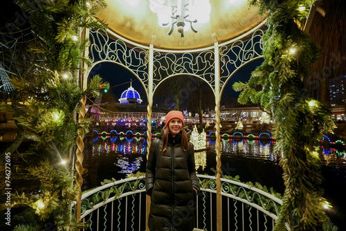 Christmas amusement park. A woman stands in the gazebo in the evening.