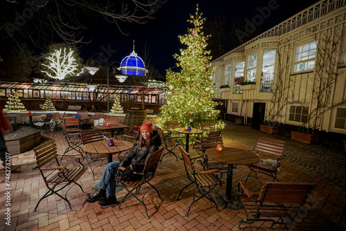 Christmas amusement park. A woman sits in an empty street cafe in the evening.