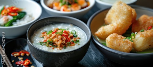 A black table is covered with bowls filled with Thai congee and fried batter known as Patongo. The bowls contain steaming hot and appetizing food, ready to be enjoyed.