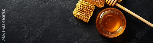 : An enticing top view banner design featuring a jar of honey with a honeycomb on a sleek black table. 