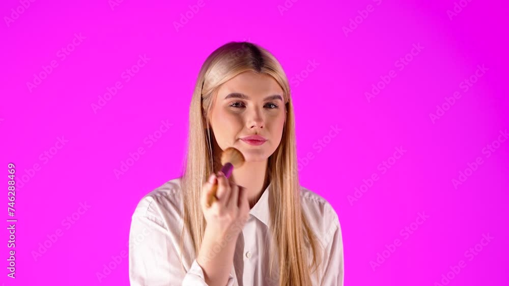 European woman looking at camera and applying makeup with cosmetic brush European woman looking at camera and applying makeup with cosmetic brush