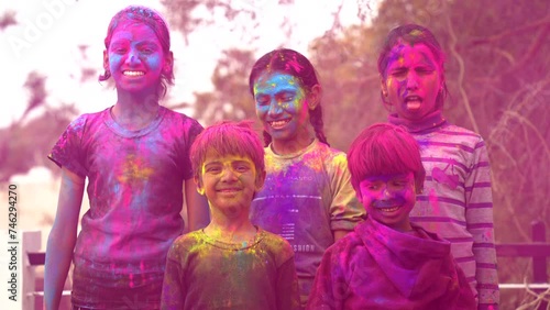 Happy Cute Indian kids applying colours on each other on the occasion of colors festival holi photo