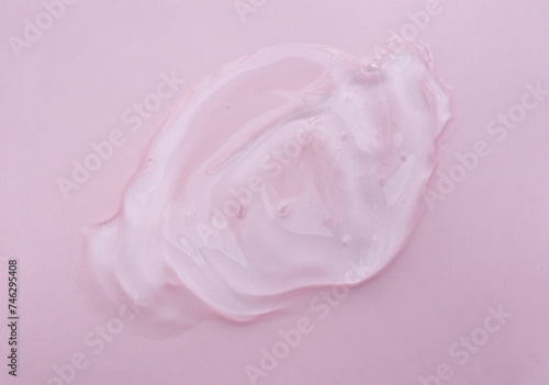 Cosmetic gel for face and body. Liquid cosmetic gel or serum lotion texture smudge on a pink background.Gel texture with bubbles 