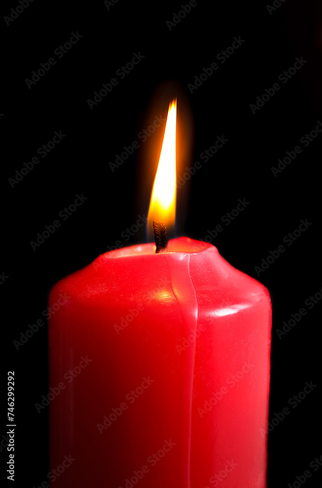 Red candle on black background. Christmas candle on dark background side closeup view Red candle on black background. Christmas candle on dark background side closeup view