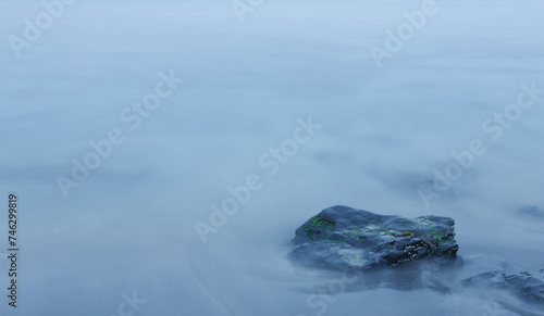 Rock in blurred out sea due to long-exposure phothgraph photo