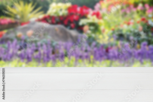 Wooden white empty table in outdoor blurred colourful flowers background. empty rustic wooden table. Mock up for display of product.