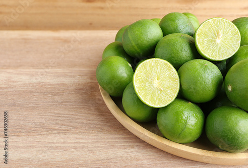 Natural fresh lime and lime cut in half on wooden table. Fresh ripe green limes on wooden table