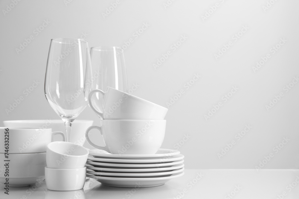 Set of many clean dishware and glasses on light table. Space for text Set of many clean dishware and glasses on light table. Space for text