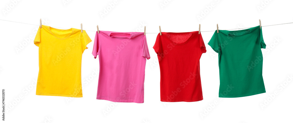 Different bright t-shirts drying on washing line against white background