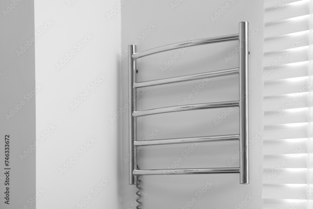 Heated towel rail on white wall in bathroom Heated towel rail on white wall in bathroom