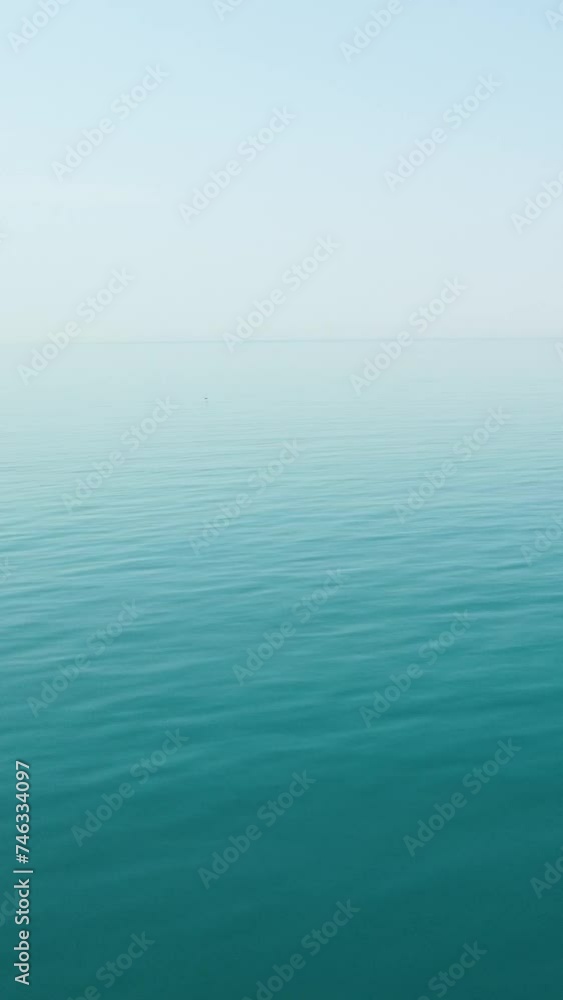 Vertical aerial view over calm azure sea water surface. Sun glare. Abstract nautical summer ocean nature. Holiday, vacation and travel concept. Nobody. Weather and climate change Vertical aerial view over calm azure sea water surface. Sun glare. Abstract nautical summer ocean nature. Holiday, vacation and travel concept. Nobody. Weather and climate change