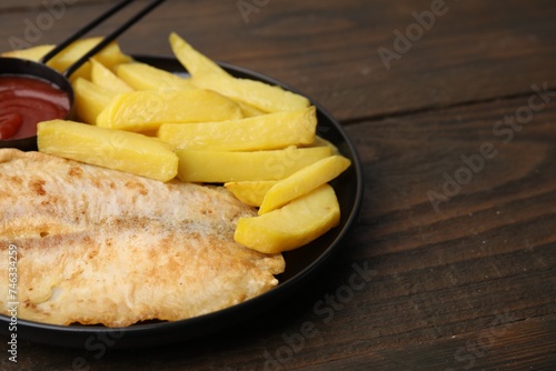 Delicious fish and chips with ketchup on wooden table, closeup