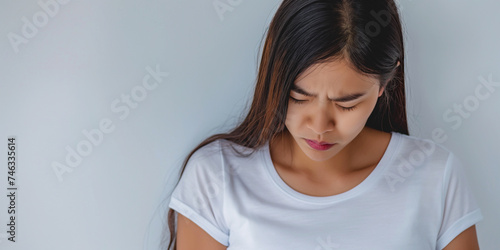 Studio portrait of young Asian girl with migraine headache, frowning with pain, white background photo